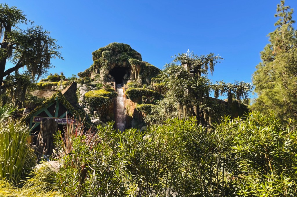 Using the facade of Splash Mountain, Tiana's Bayou Adventure is a greenery-covered mountain against the blue sky.