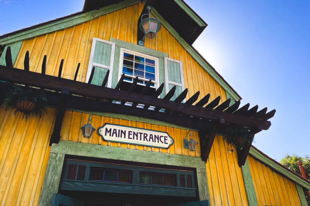 A yellow building with green trim is marked with "Main Entrance"